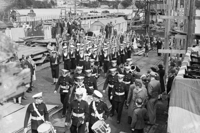 Royal Marine Band at ease after the delivery ceremony for HMNZS Waikato (T30) in 1944. The Royal Marines served with the RNZN for 36 years prior to when our own RNZN band was established in 1960. HNZS Waikato (I) was never commissioned into the RNZN as she was considered surplus to the war effort. Image: 2013.70.2659 Royal Marine Band at ease after the delivery ceremony for HMNZS Waikato (T30) in 1944. The Royal Marines served with the RNZN for 36 years prior to when our own RNZN band was established in 1960. HNZS Waikato (I) was never commissioned into the RNZN as she was considered surplus to the war effort.