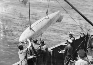 Minesweeper crew retrieving an oropesa sweep which is attached to sweep wired cutters and stablised by a minesweeping kite or otter.