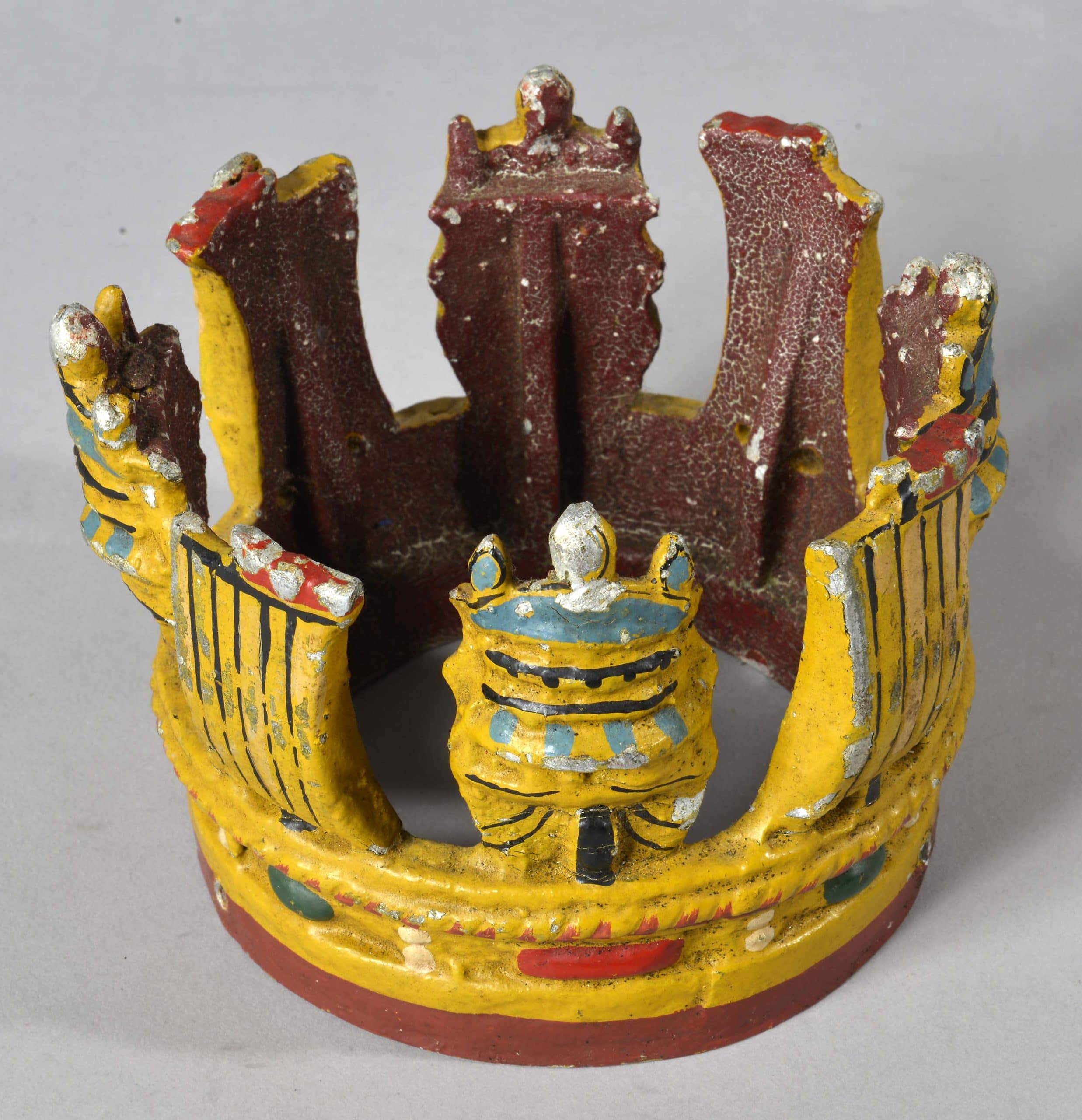 Metal painted crown attached to short section of wooden masthead. Masthead crown is believed to have been from HMS New Zealand.
